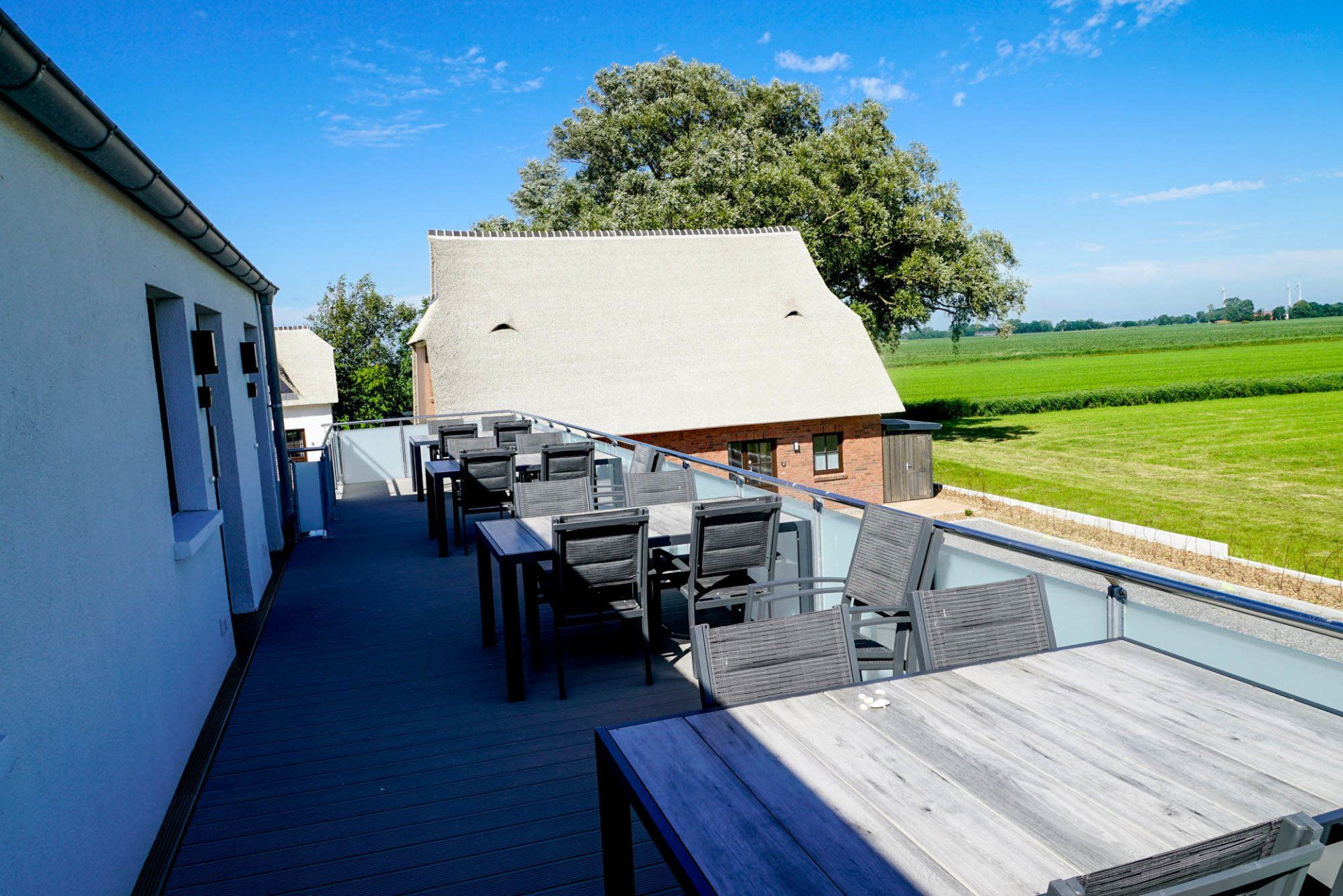 Langer Balkon oder Dachterrasse mit Sitzgruppen und Blick über die Anlage.