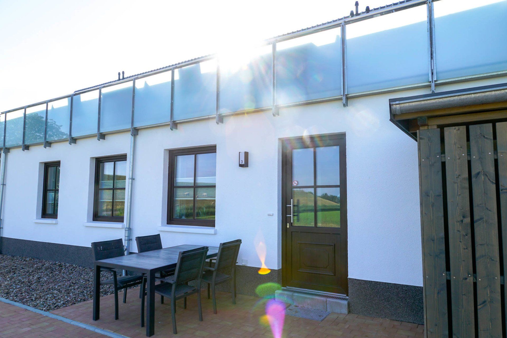 Terrasse an einem Ferienhaus mit Tisch und Stühlen in der Sonne.