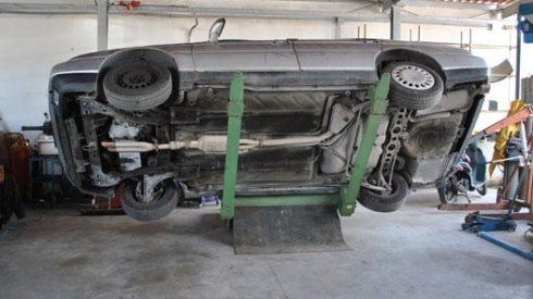 Un'auto viene sollevata capovolta in un garage.