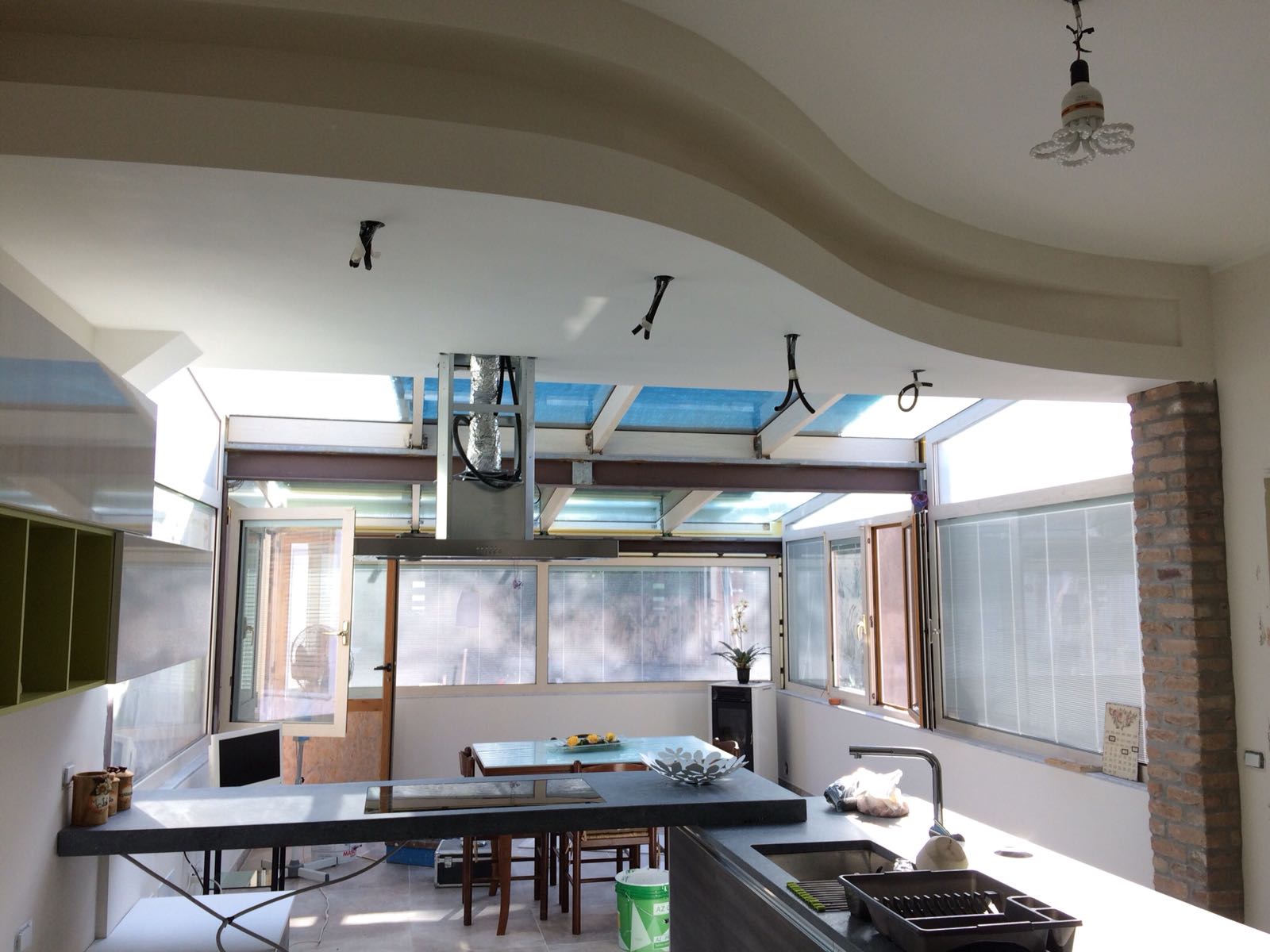 Cucina con finestre aperte, lucernari ed elettrodomestici in acciaio inossidabile. È presente un soffitto ondulato.