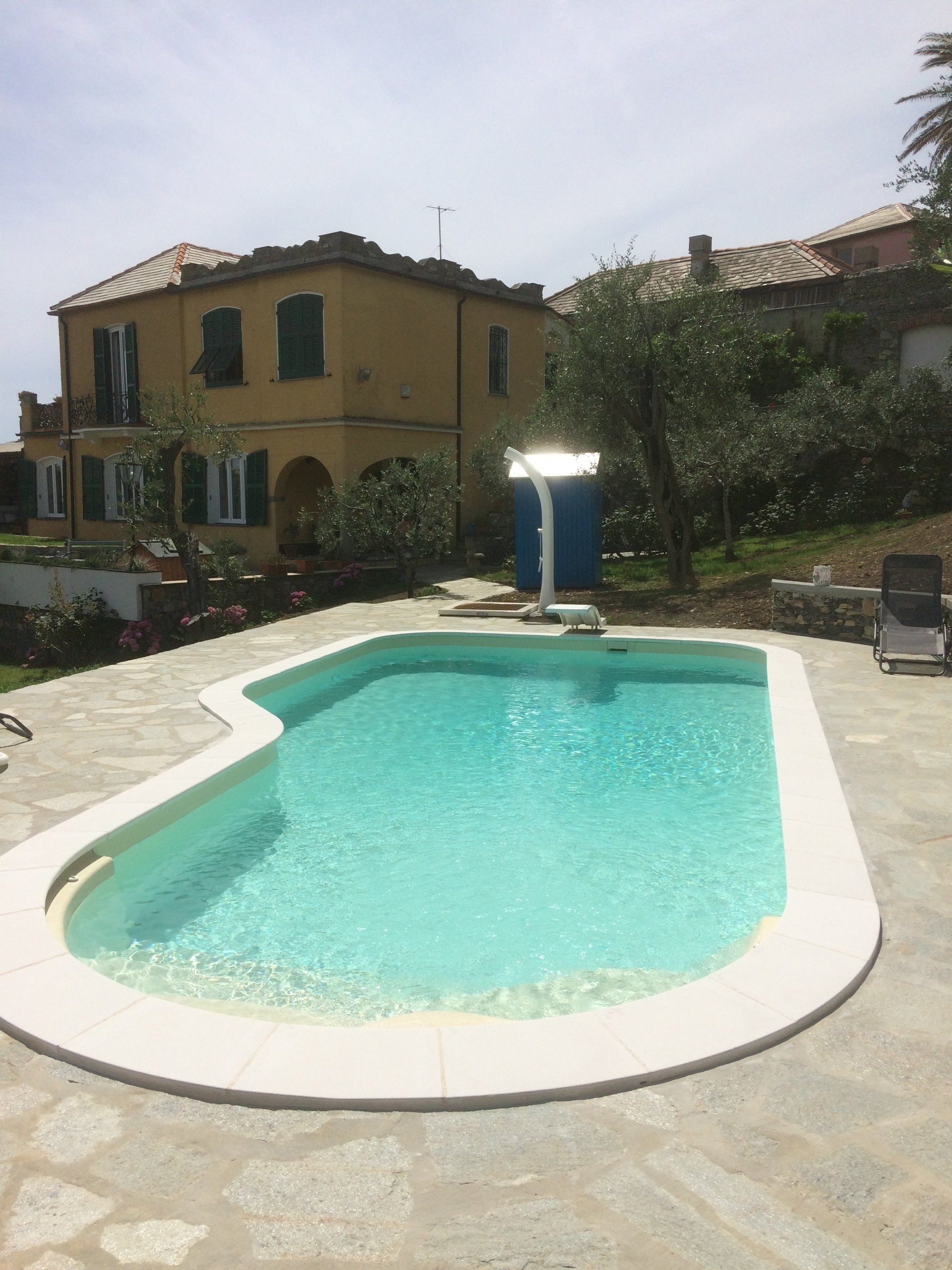 Piscina di fronte a una casa gialla in una giornata di sole.