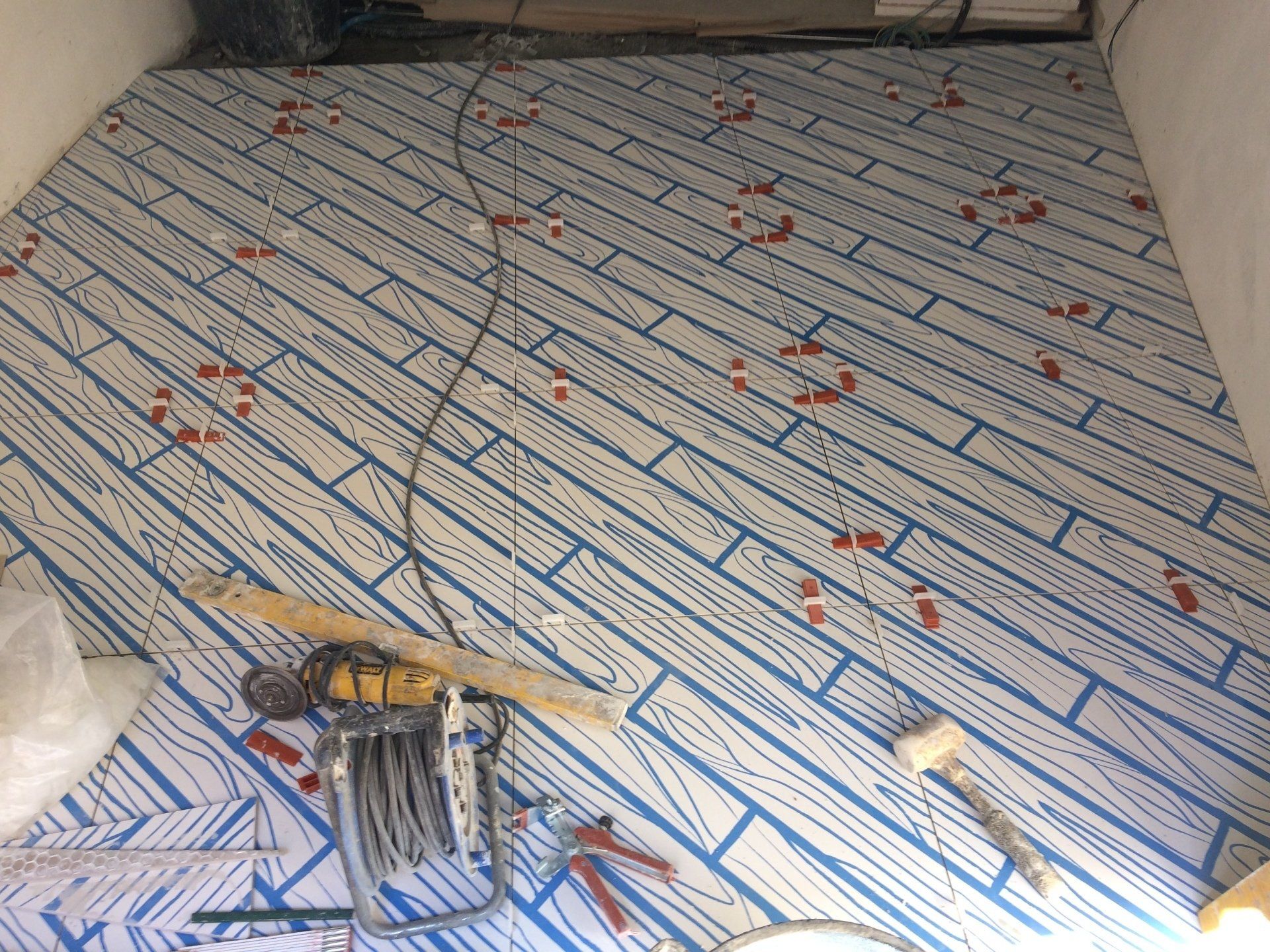 Pavimento con motivo diagonale effetto legno blu, attrezzi da costruzione e macchie rosse.