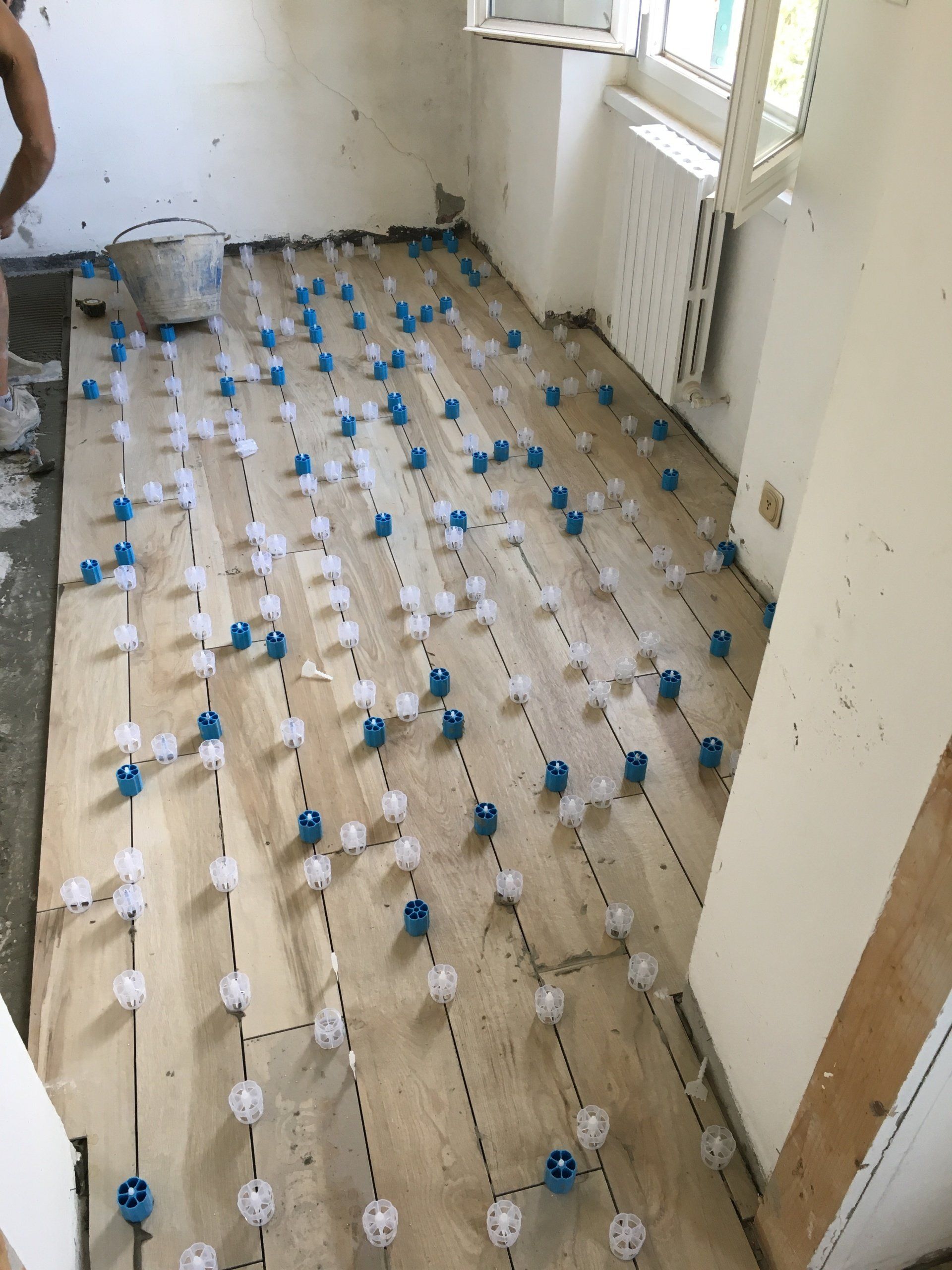Piastrelle per pavimenti con clip di livellamento blu e bianche installate in una stanza.