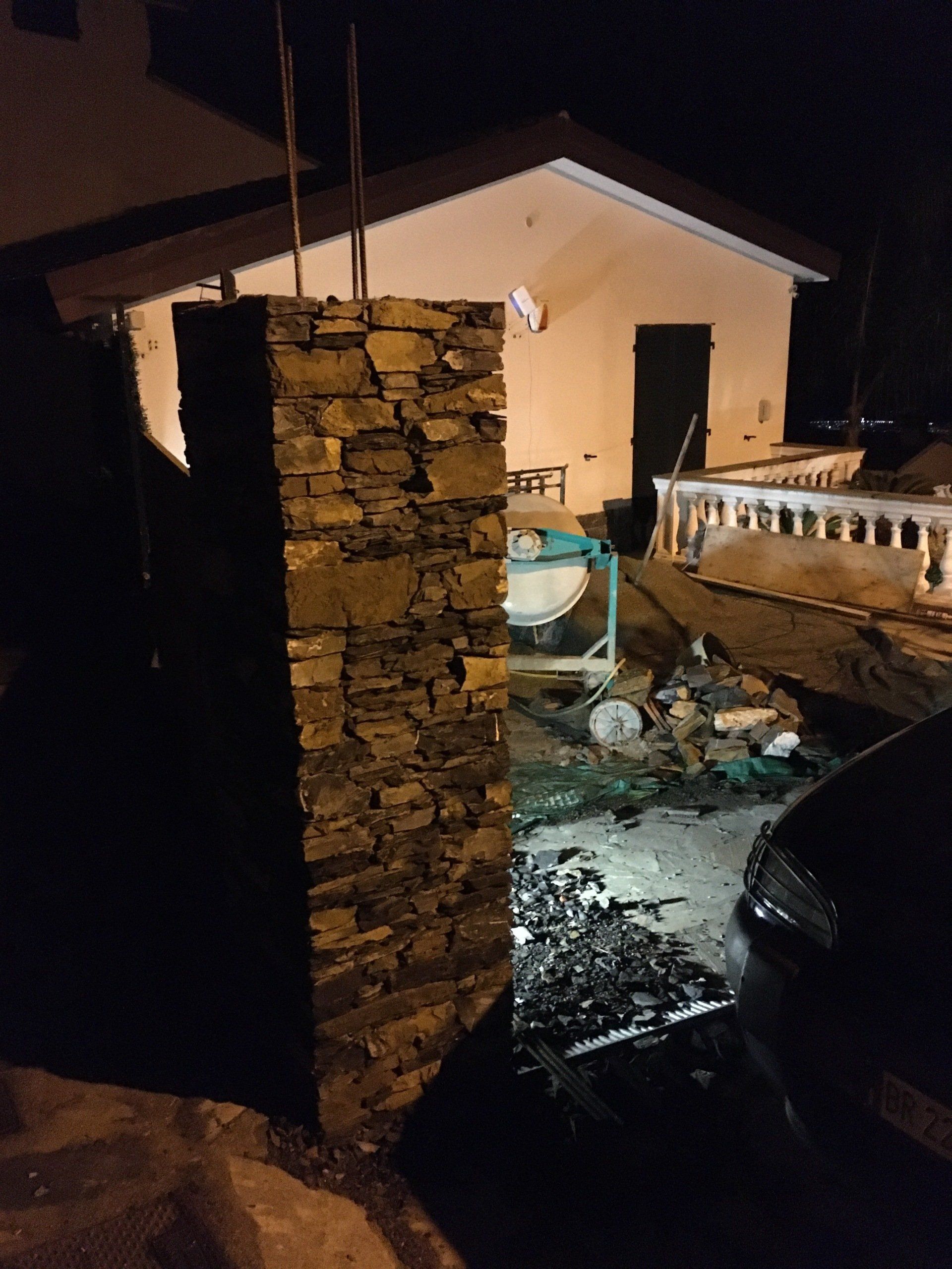 Pilastro di pietra di fronte a un edificio color marrone con attrezzature edili di notte.