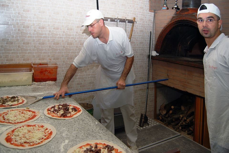 pizzaioli pronti a infornare le pizze nel forno a legna