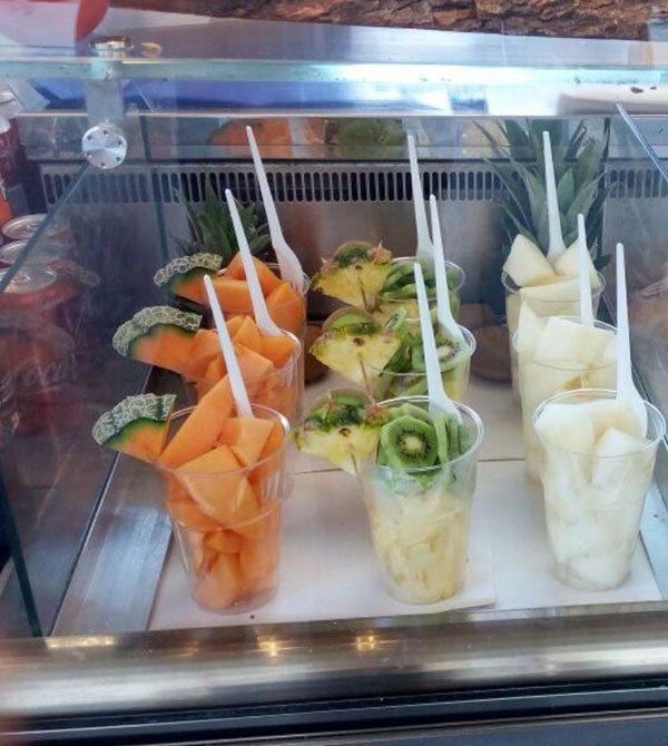 Dei bicchieri di plastica con melone, kiwi e ananas