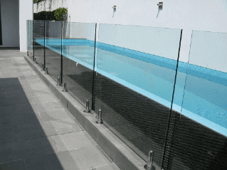 Glass pool fence along a blue-tiled pool, against a white wall.