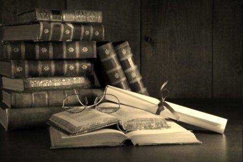 Pile of old books with glasses on desk - MA,USA