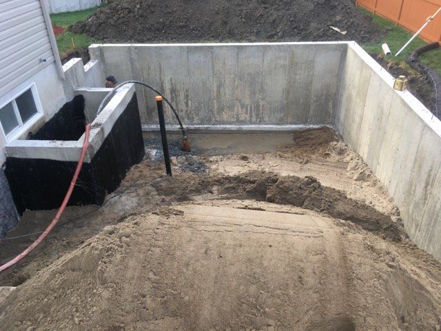 Fondations en béton et fouilles environnantes. Monticule de terre au premier plan.