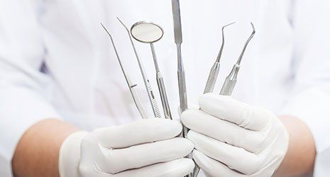 Due mani che mantengono strumenti da dentista