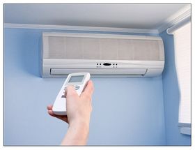 hand holding remote pointed at air conditioning unit on wall