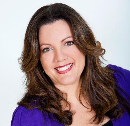 A woman in a purple shirt is smiling for the camera