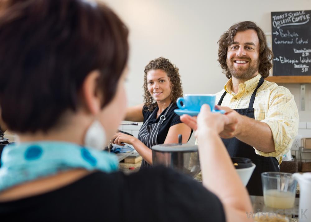 A man is serving a cup of coffee to a woman in a restaurant.
