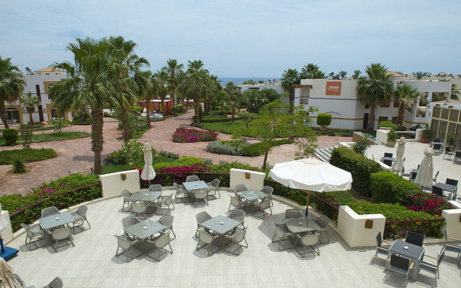 Outdoor terrace with tables and parasols surrounded by gardens at Amphoras Hotels