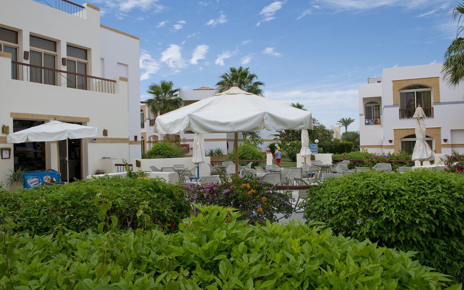 Garden seating under white parasols among the resort buildings at Amphoras Hotels