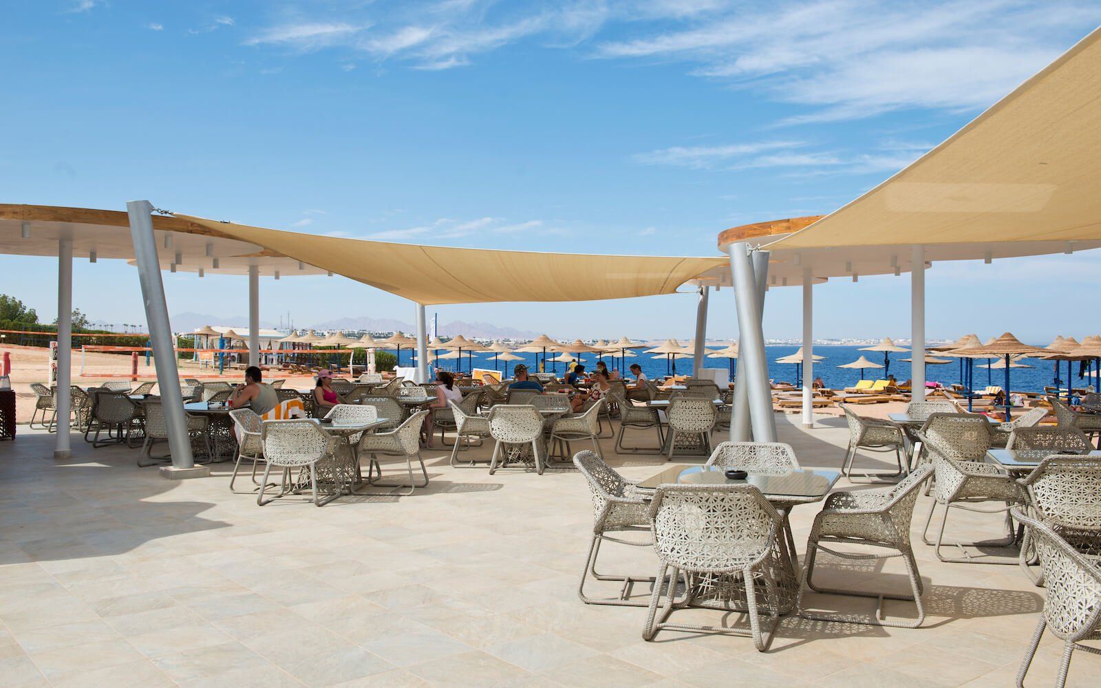 Guests enjoying the sunny beach area with views of the sea and clear skies.