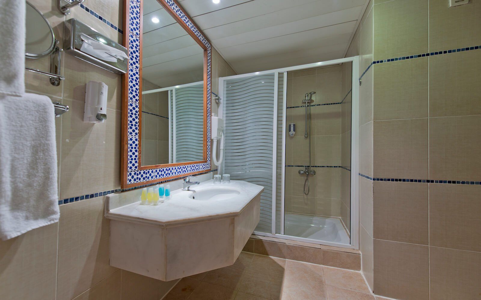 Modern hotel bathroom with walk-in shower and marble countertop.
