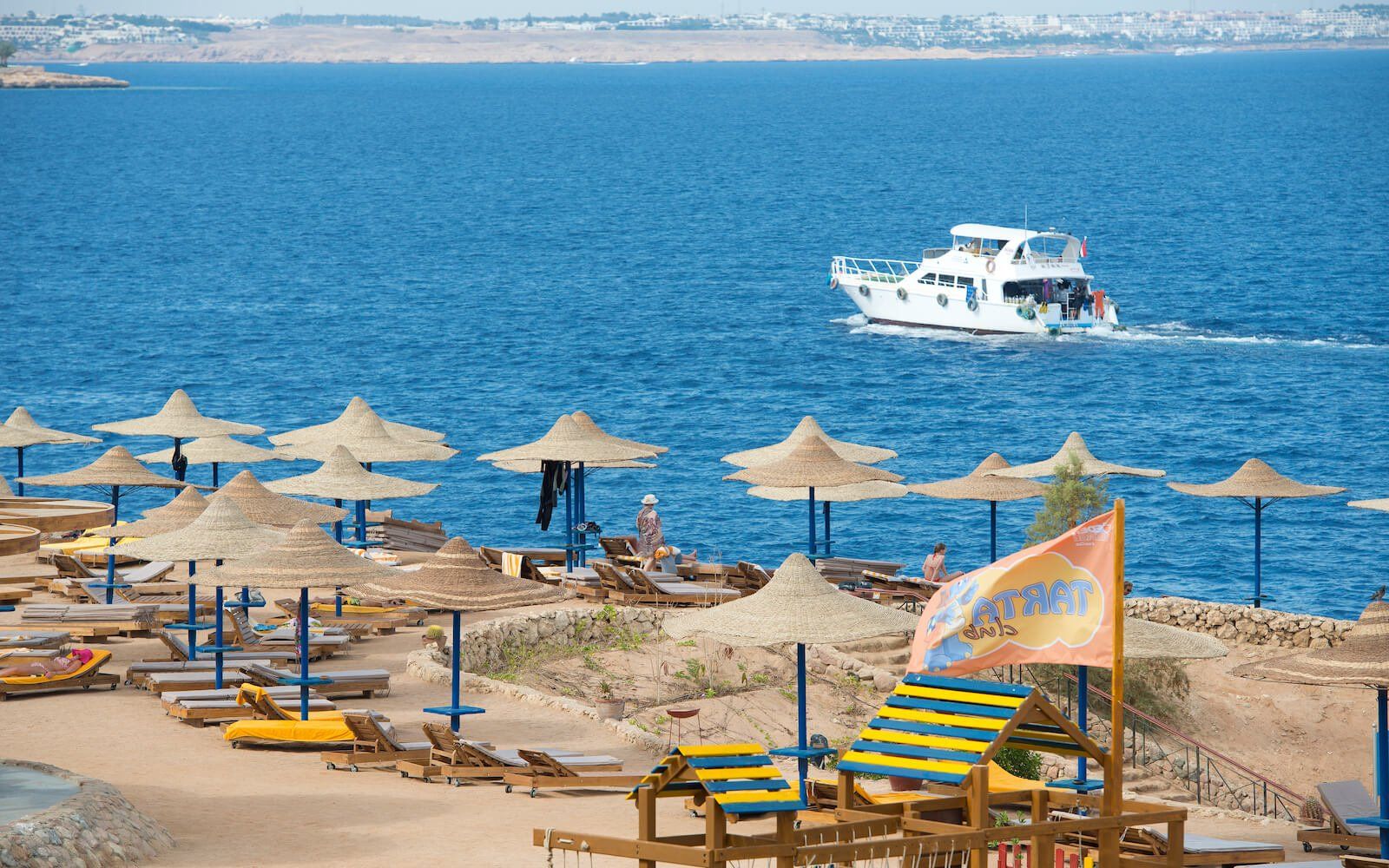 Scenic sea view with a small yacht and coral rocks on the coastline.