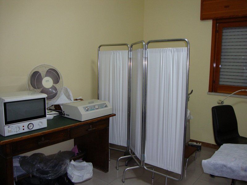 Sala visite mediche con attrezzatura, schermo per la privacy e finestra.