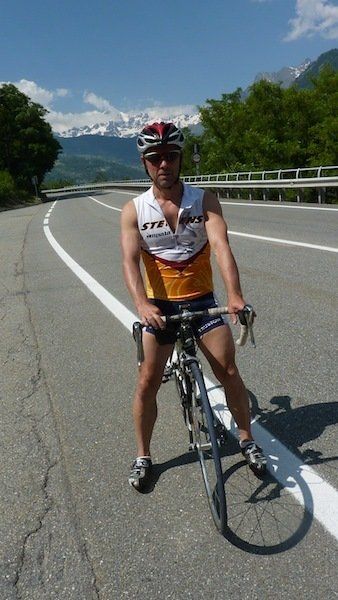 A man riding a bike on a road with mountains in the background