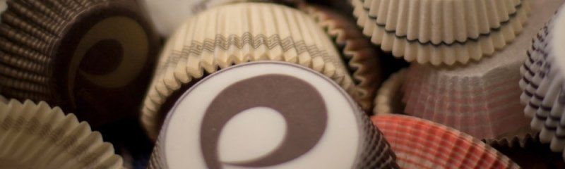 Un primo piano di cioccolatini assortiti con incarti decorativi in carta ondulata nelle tonalità del bianco, del marrone e del rosa.