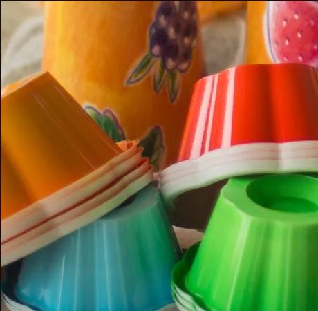Un assortimento colorato di stampini per gelatina in plastica scanalata e impilabili, nei colori arancione, rosso, verde e blu.