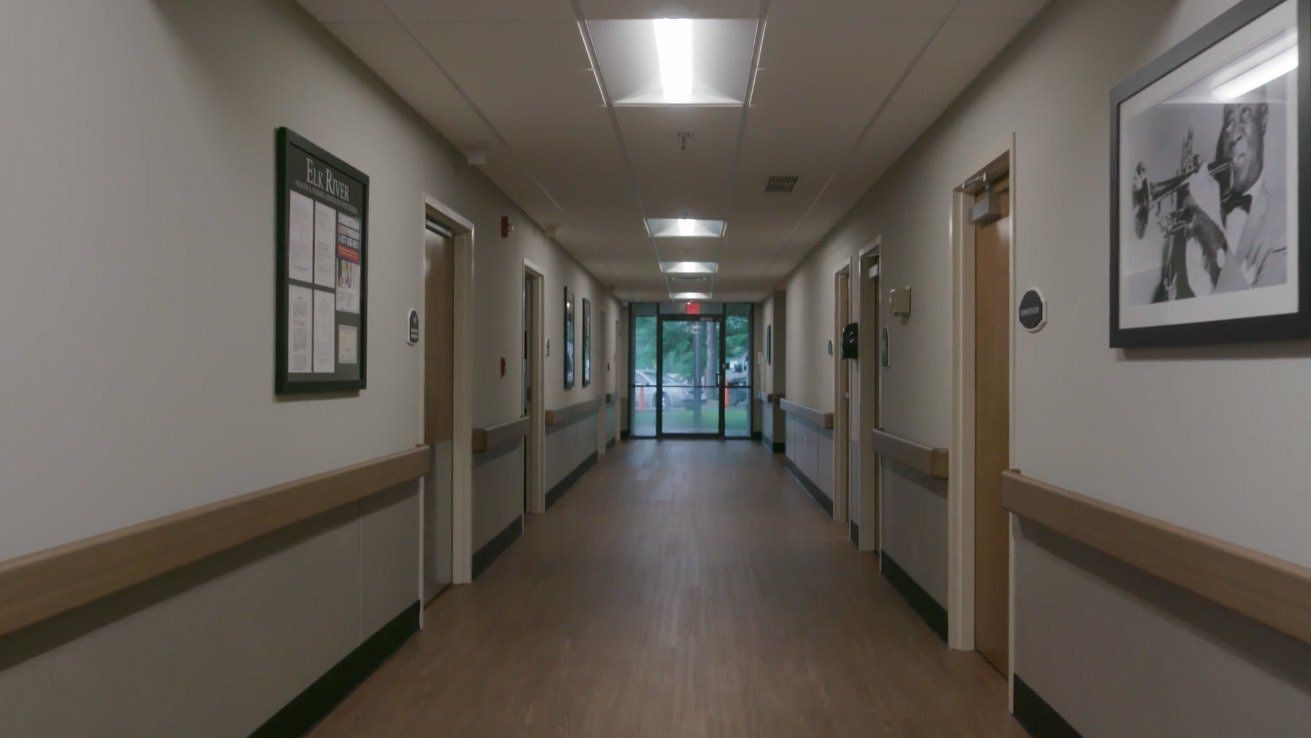 A long hallway in a hospital with a picture on the wall.