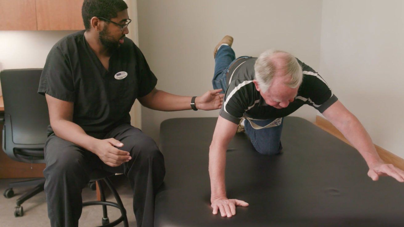 A man is doing exercises on a table while a doctor watches.