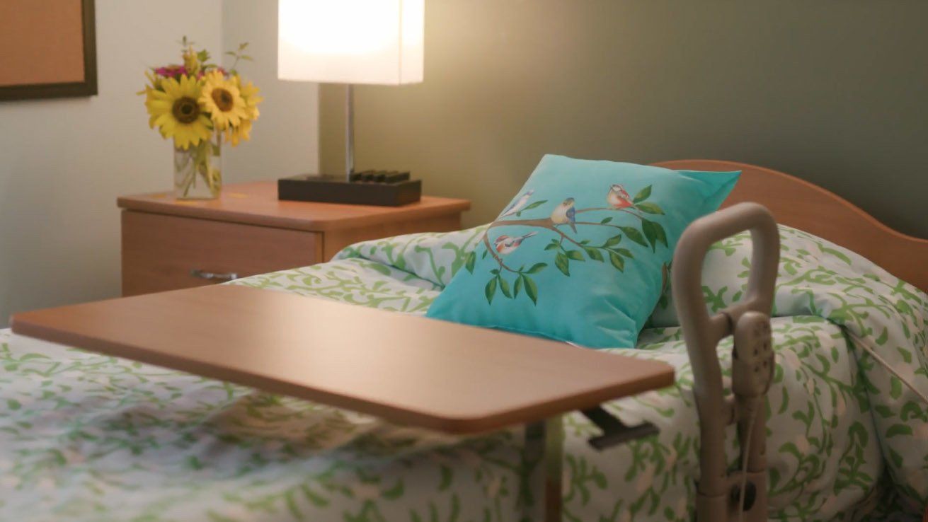 A hospital bed with a table and a pillow on it.