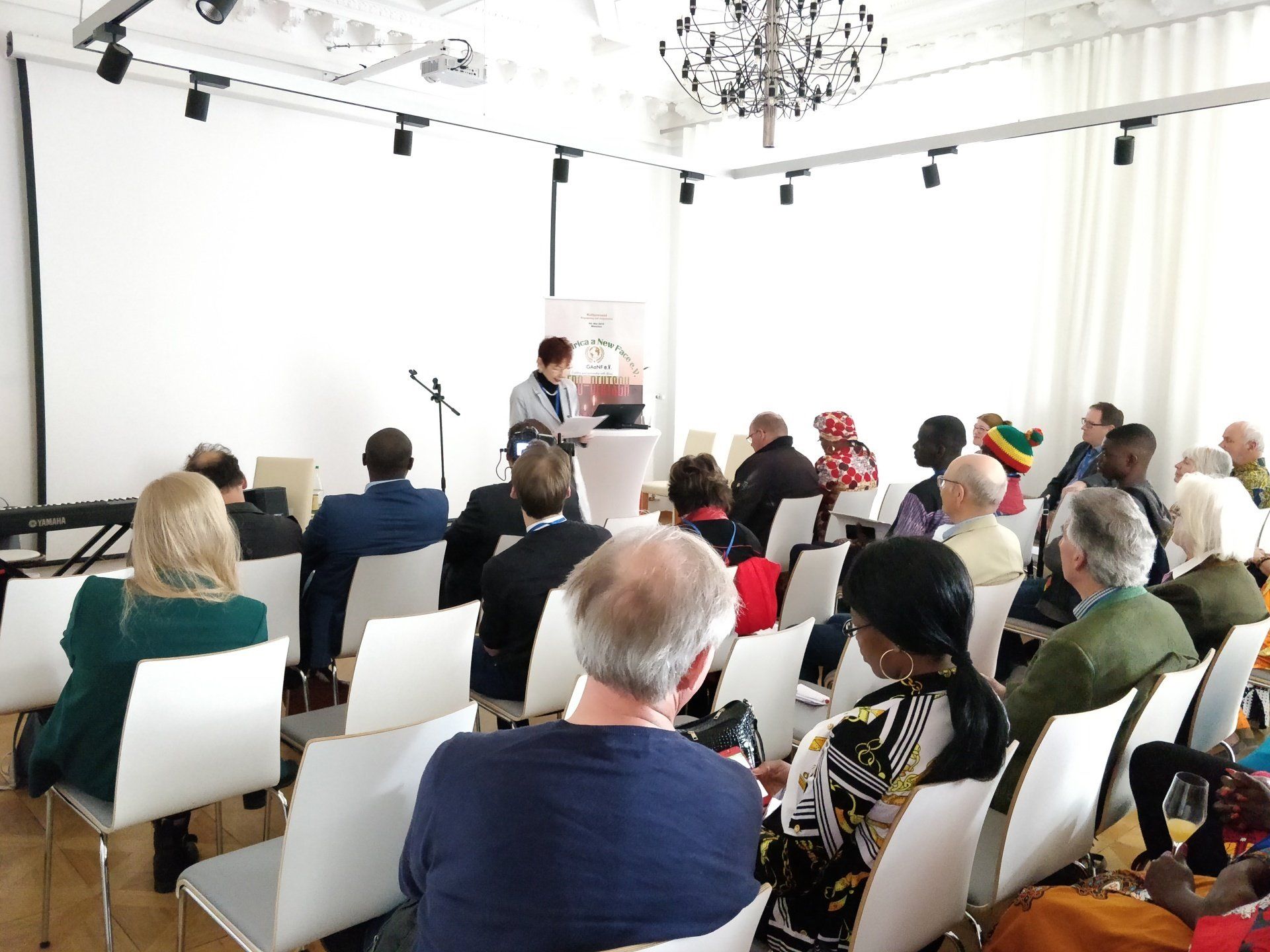 A group of people are sitting in chairs in a room watching a presentation.