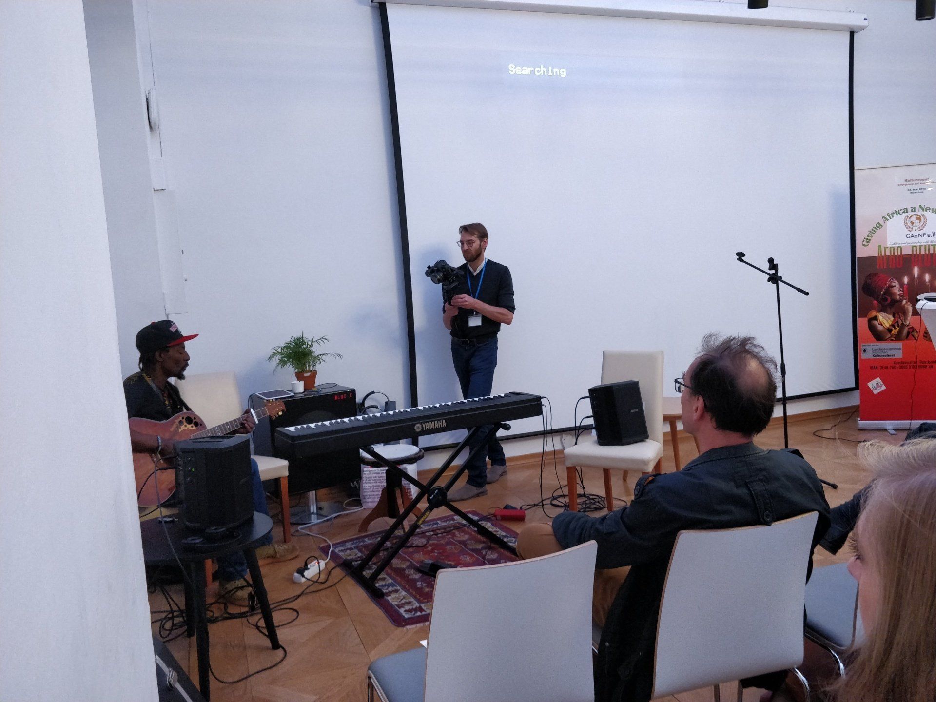 A man is standing in front of a projector screen holding a camera