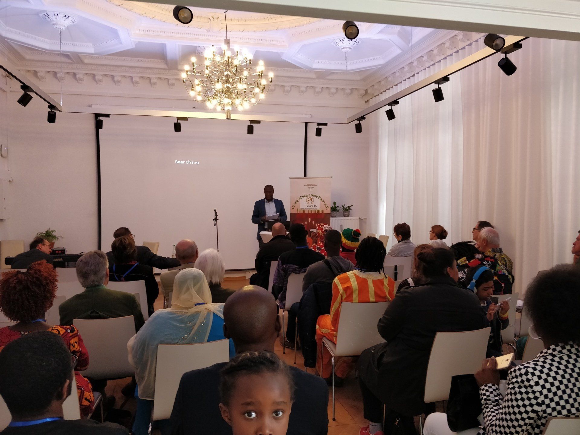 A group of people are sitting in chairs in a room watching a presentation.