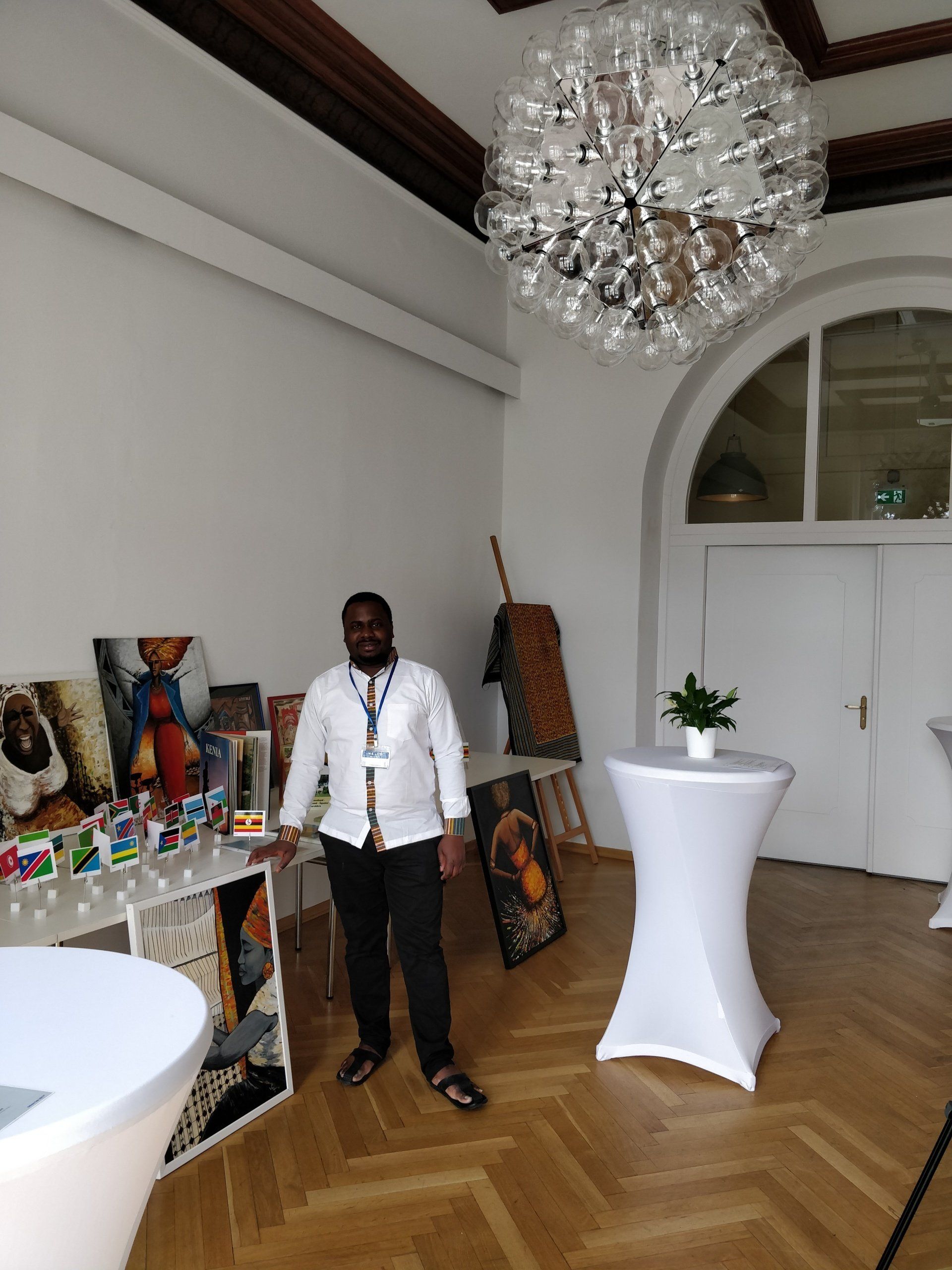 A man is standing in a room with tables and a chandelier.