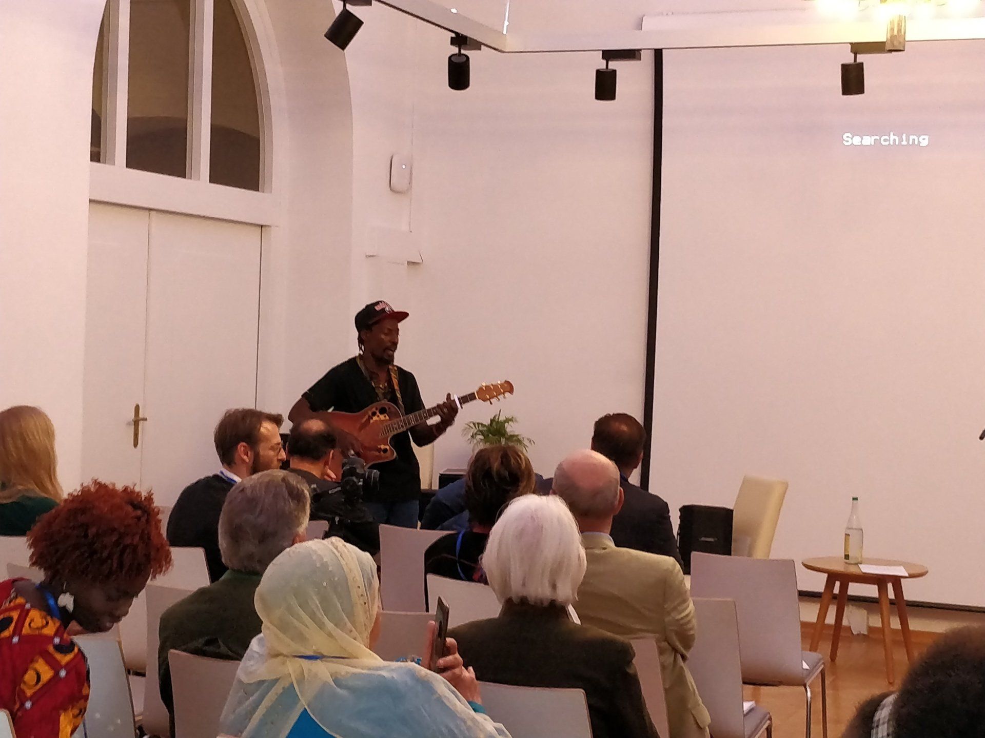 A man is playing a guitar in front of a group of people