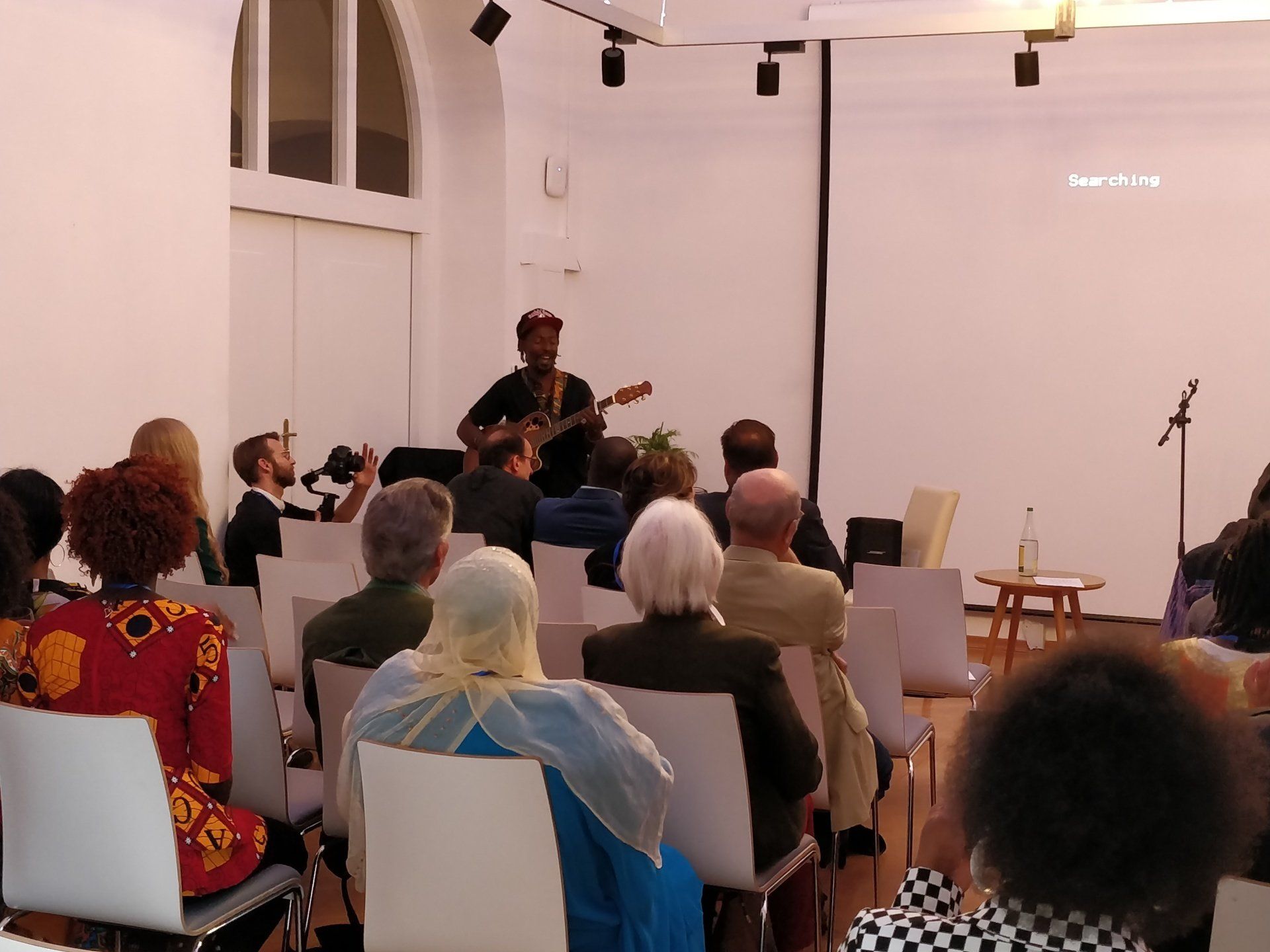 A man is playing a guitar in front of a crowd of people