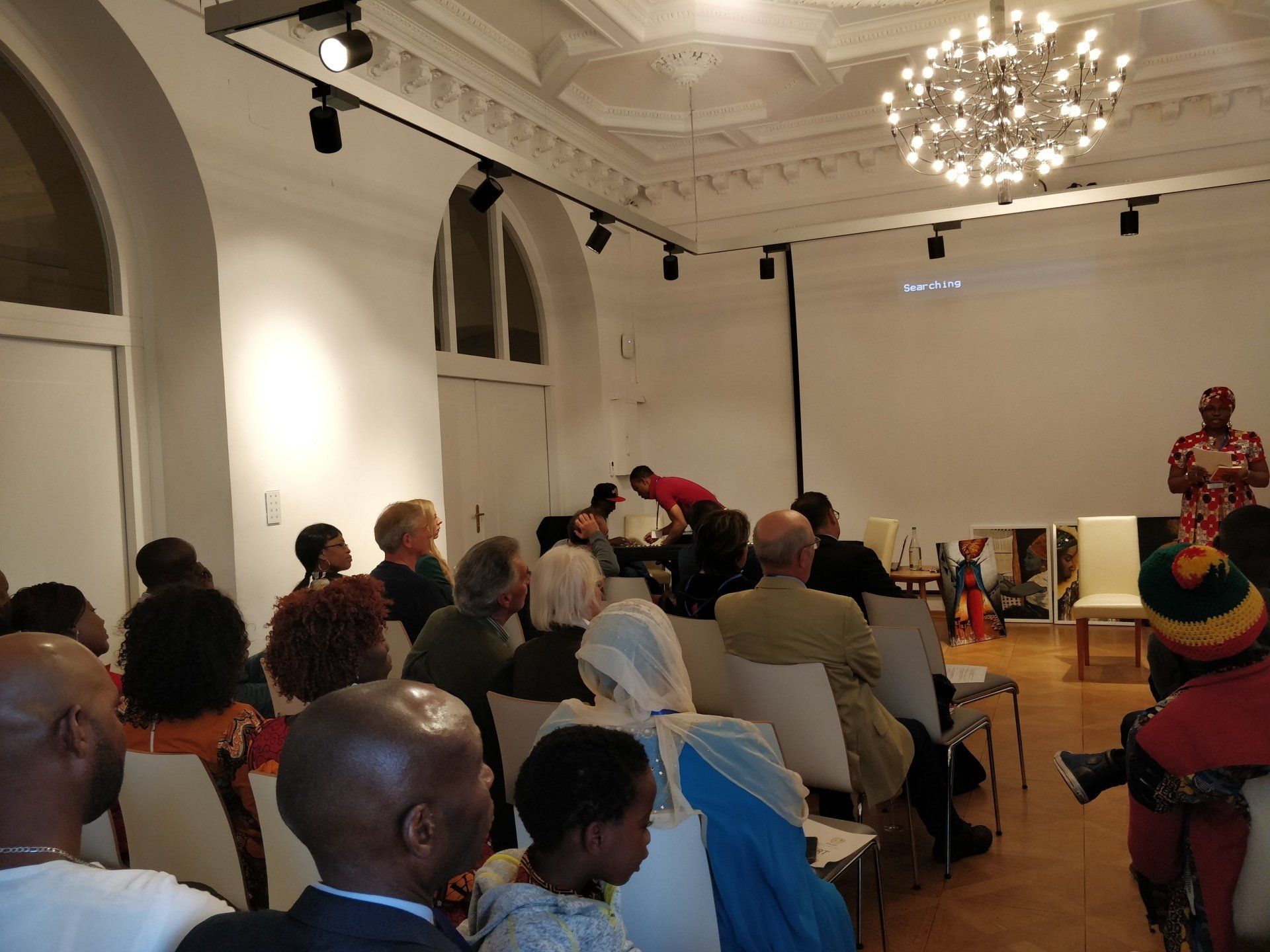 A group of people are sitting in chairs in a room watching a presentation.