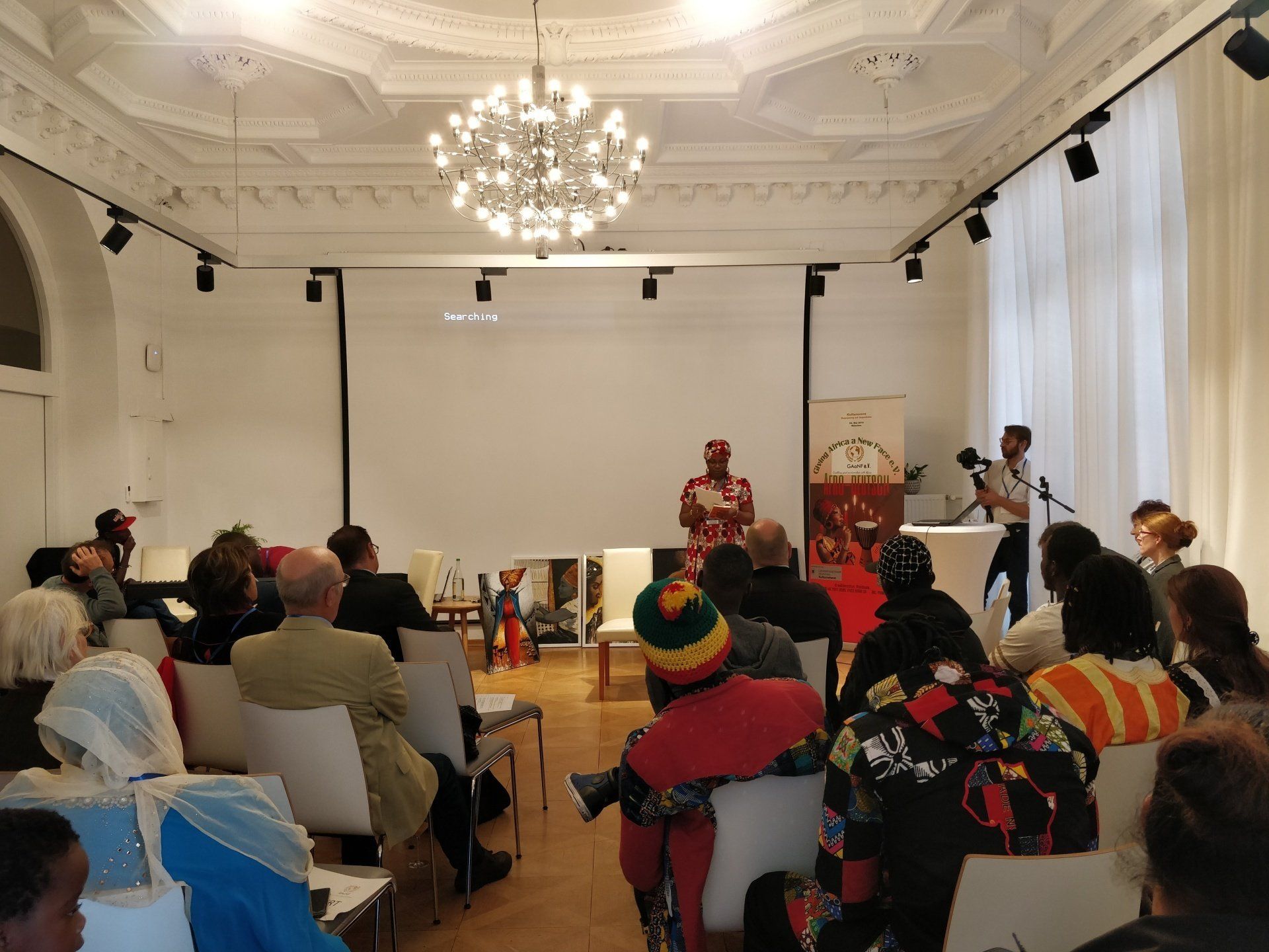 A man in a rasta hat is giving a presentation to a group of people
