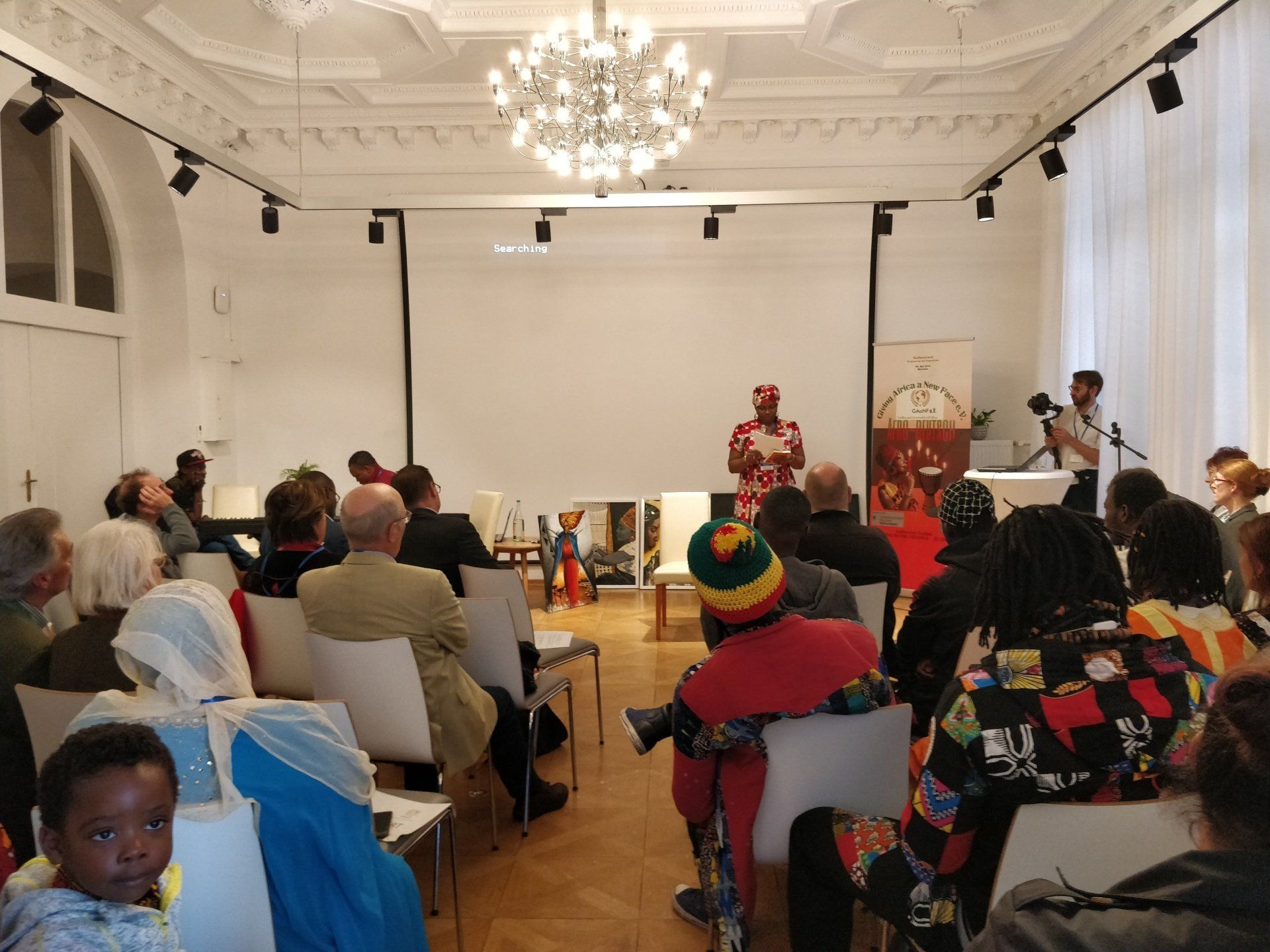 A group of people are sitting in a large room watching a presentation