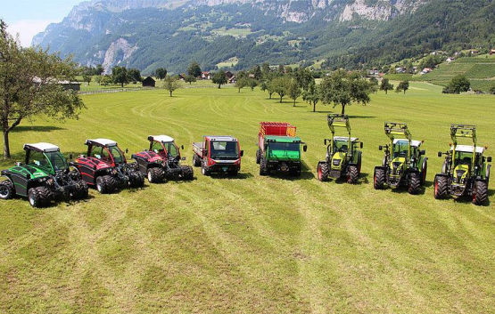 Auf einer Wiese parken mehrere Traktoren.