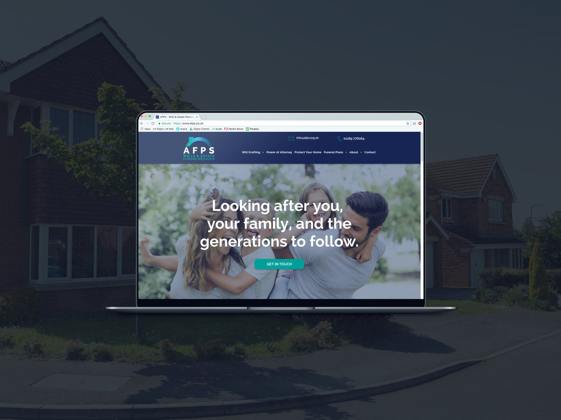 A laptop with a family on the screen is sitting in front of a house.