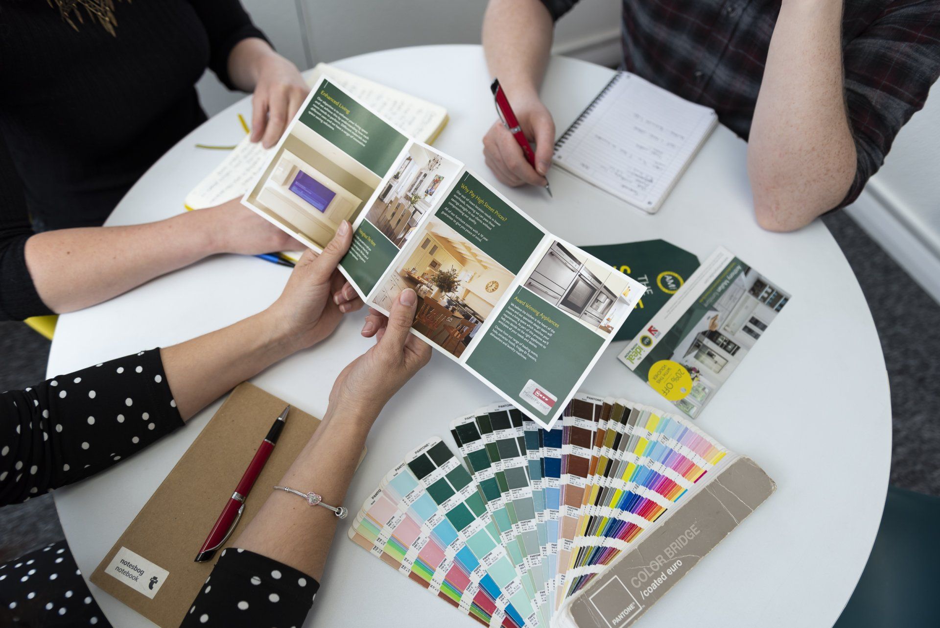 A man and a woman are sitting at a table looking at a brochure.