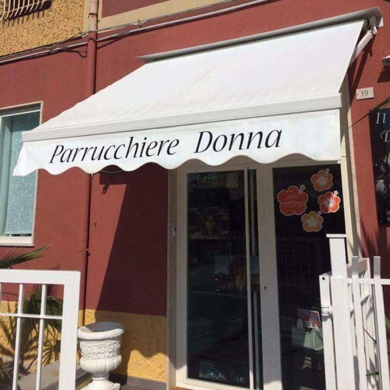 un tendone da esterno con scritto Parrucchiere Donna
