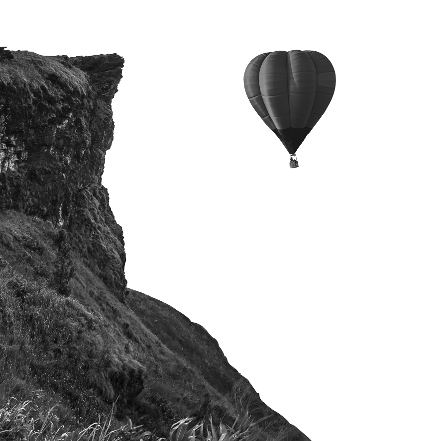 Dal fianco di una parete rocciosa in primo piano sulla sinistra, si vede in cielo sullo sfondo una mongolfiera in volo