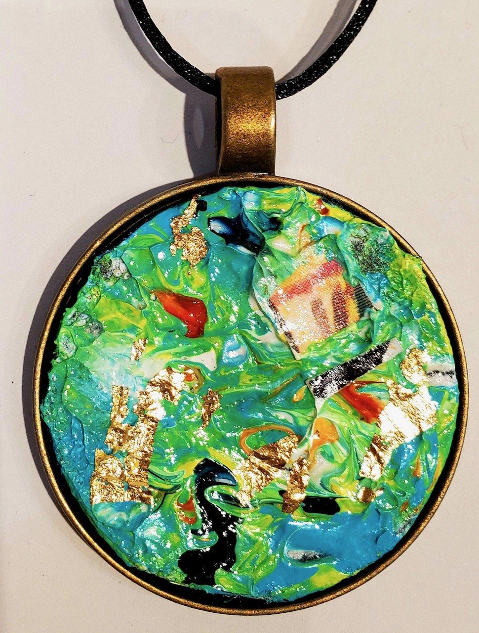A necklace with a green and blue pendant on a black cord