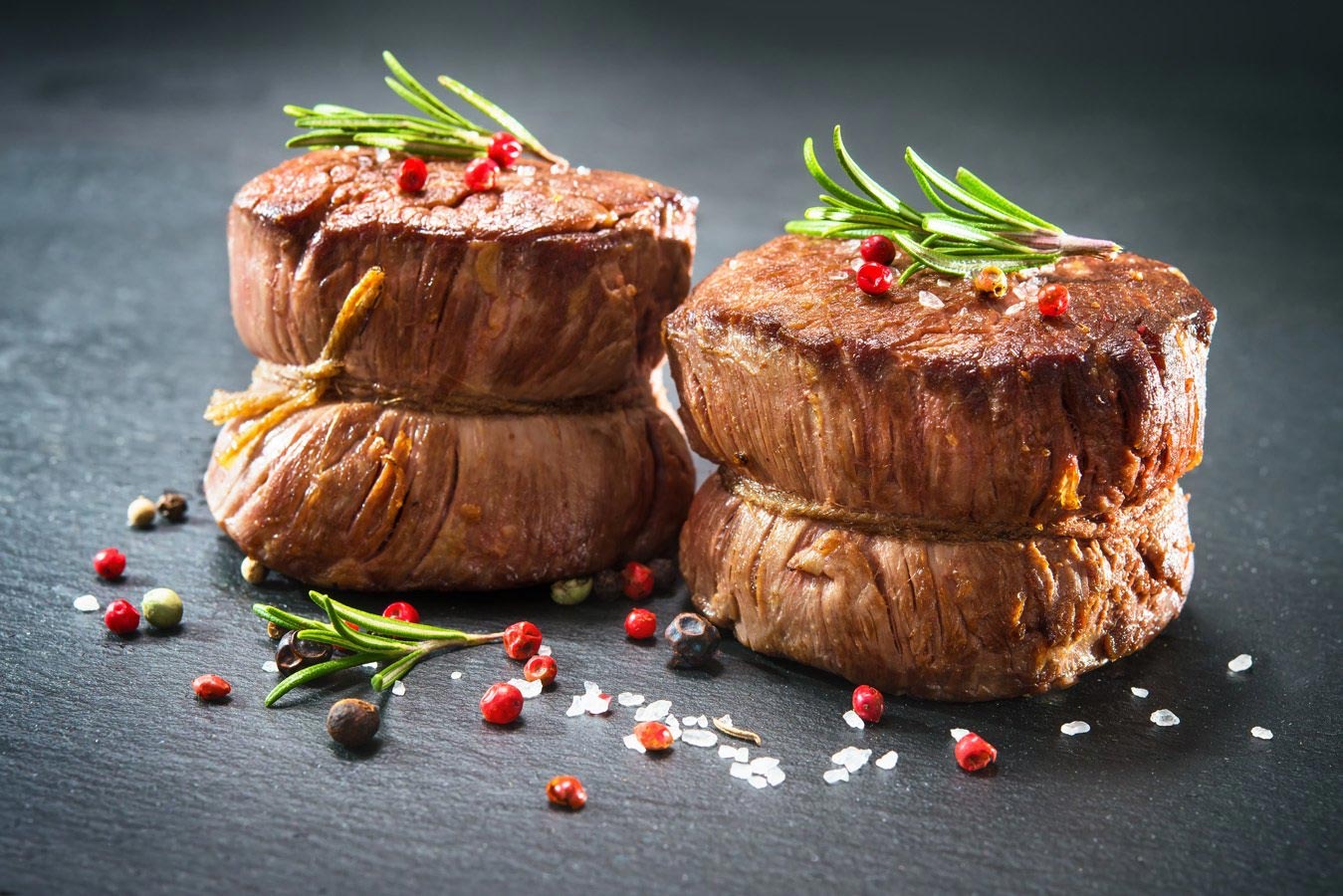 Two steaks are stacked on top of each other on a table.