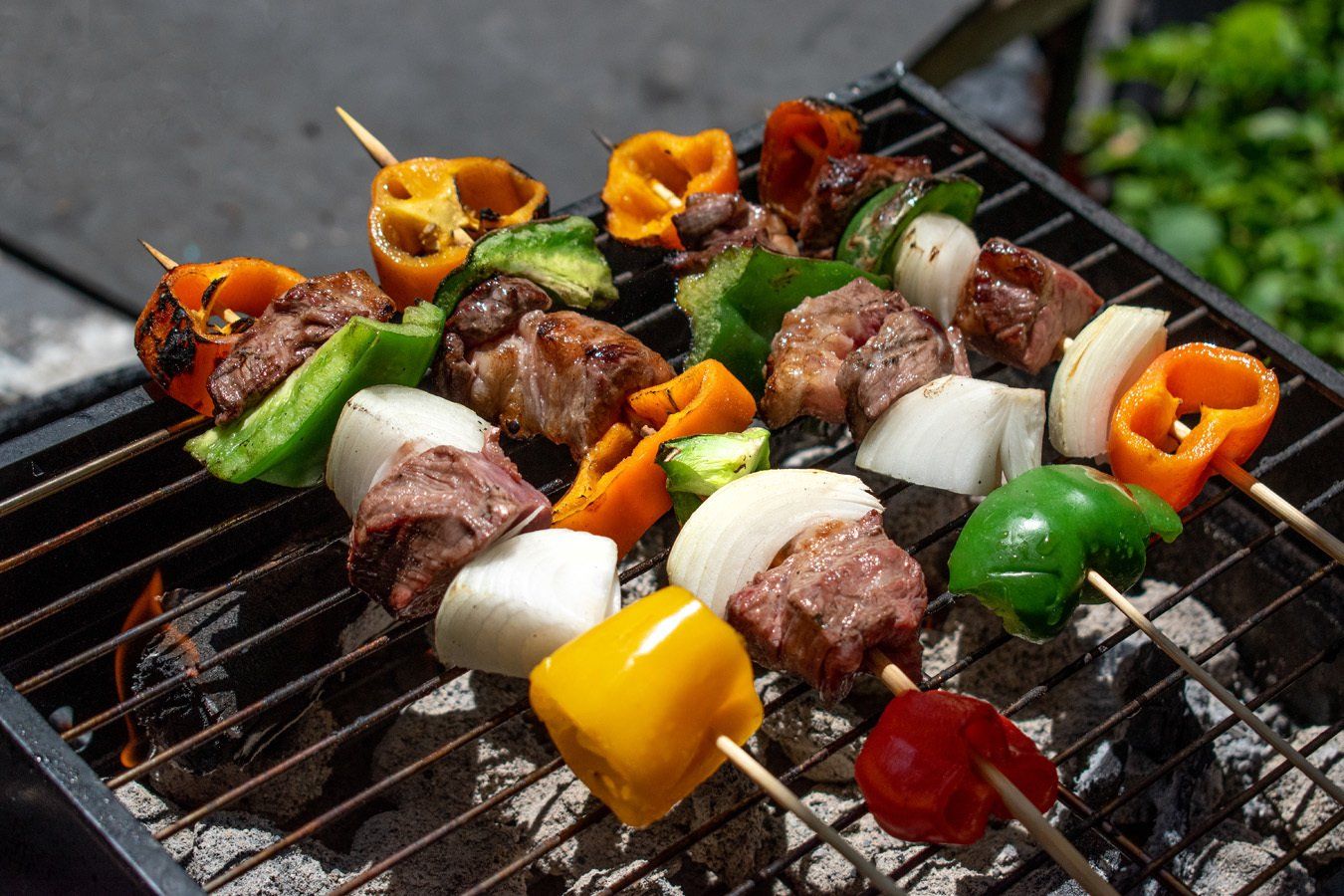 A grill with skewers of meat and vegetables on it.