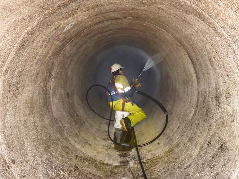 man waterblasting in concrete tube