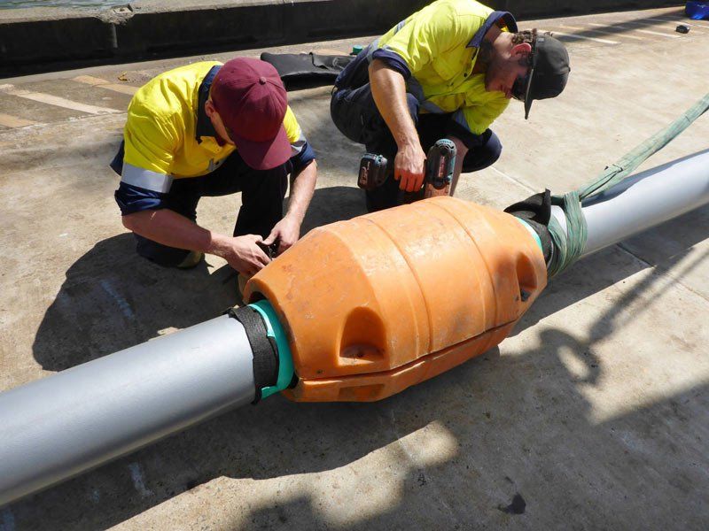 two workers working on orange pipe