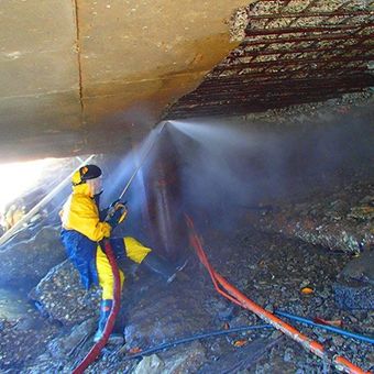 person waterblasting in metal tube