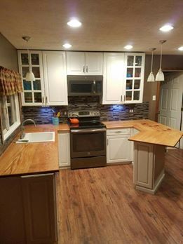 Modern kitchen with white cabinets, dark stove, wood countertops, and a small peninsula with bar stool buttons.